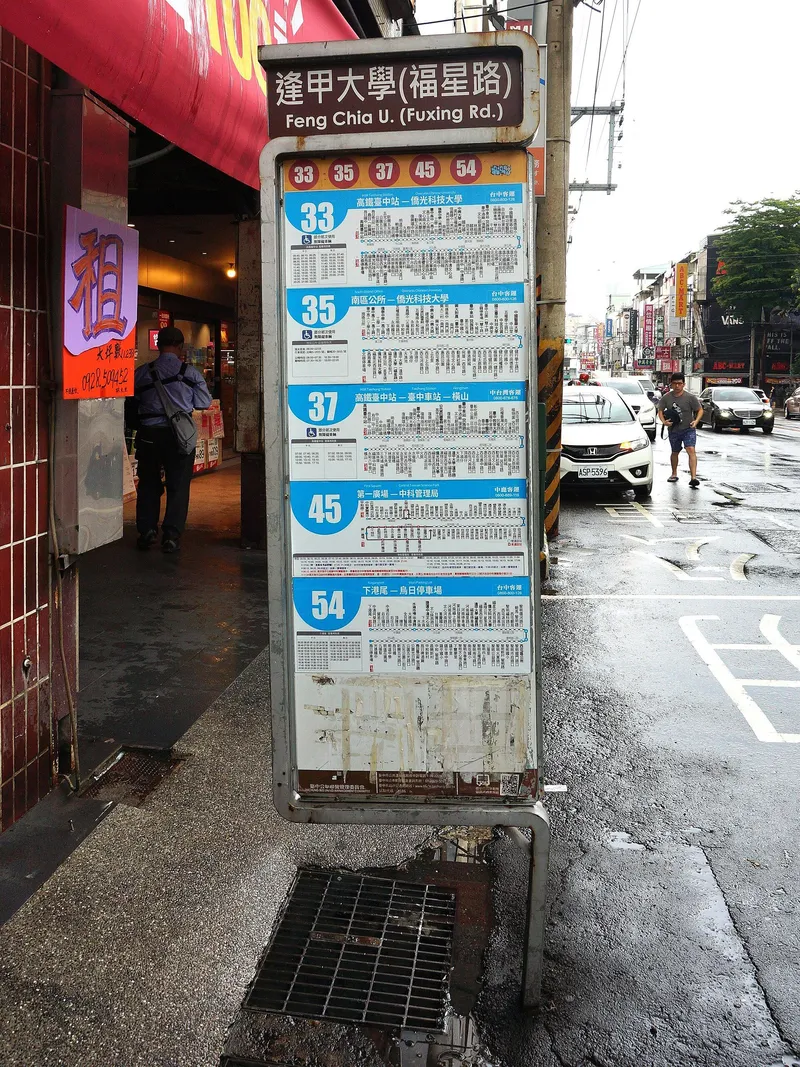 The pole at the Feng Chia U. (Fuxing Rd.) stop: circled numbers for the routes this pole carries, and below them each route's stop list and departure timetable panel.